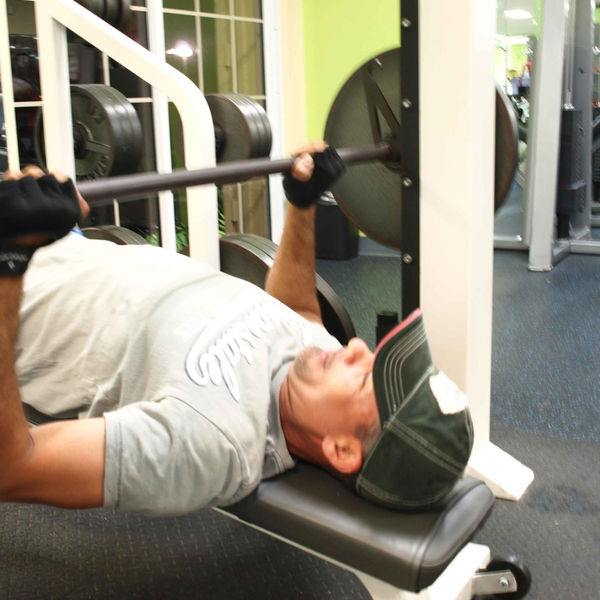 A member pressing a barbell on the bench