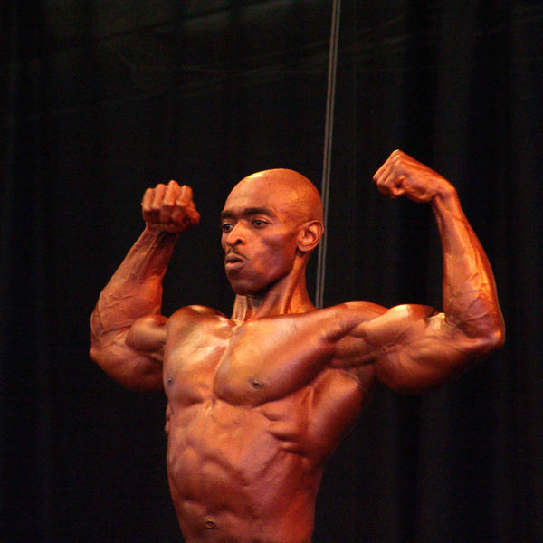 A competitor posing on stage at a bodybuilding show