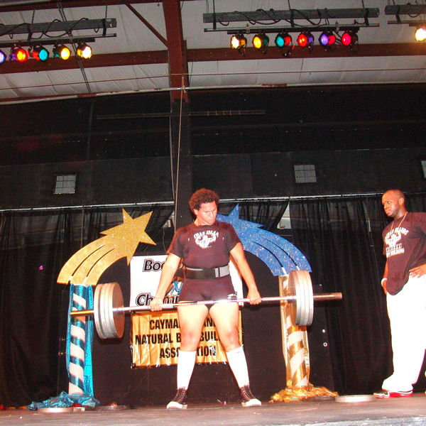 A lifter pulling a loaded barbell on stage